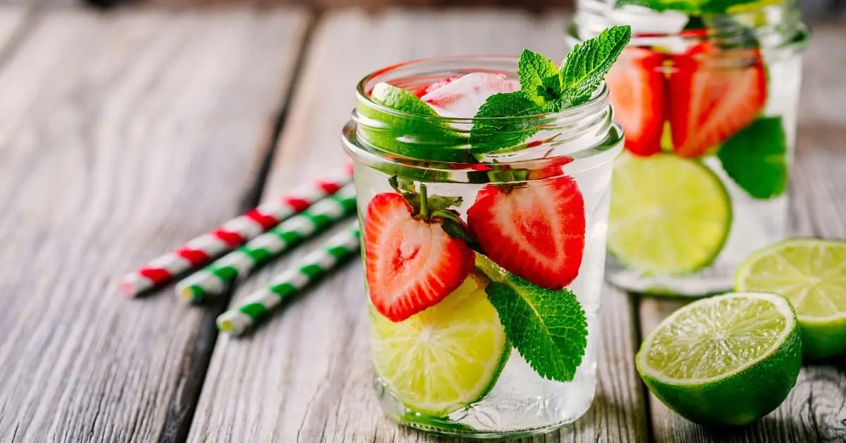 Acqua detox con fragole lime e menta in barattolo di vetro per idratazione naturale estiva.
