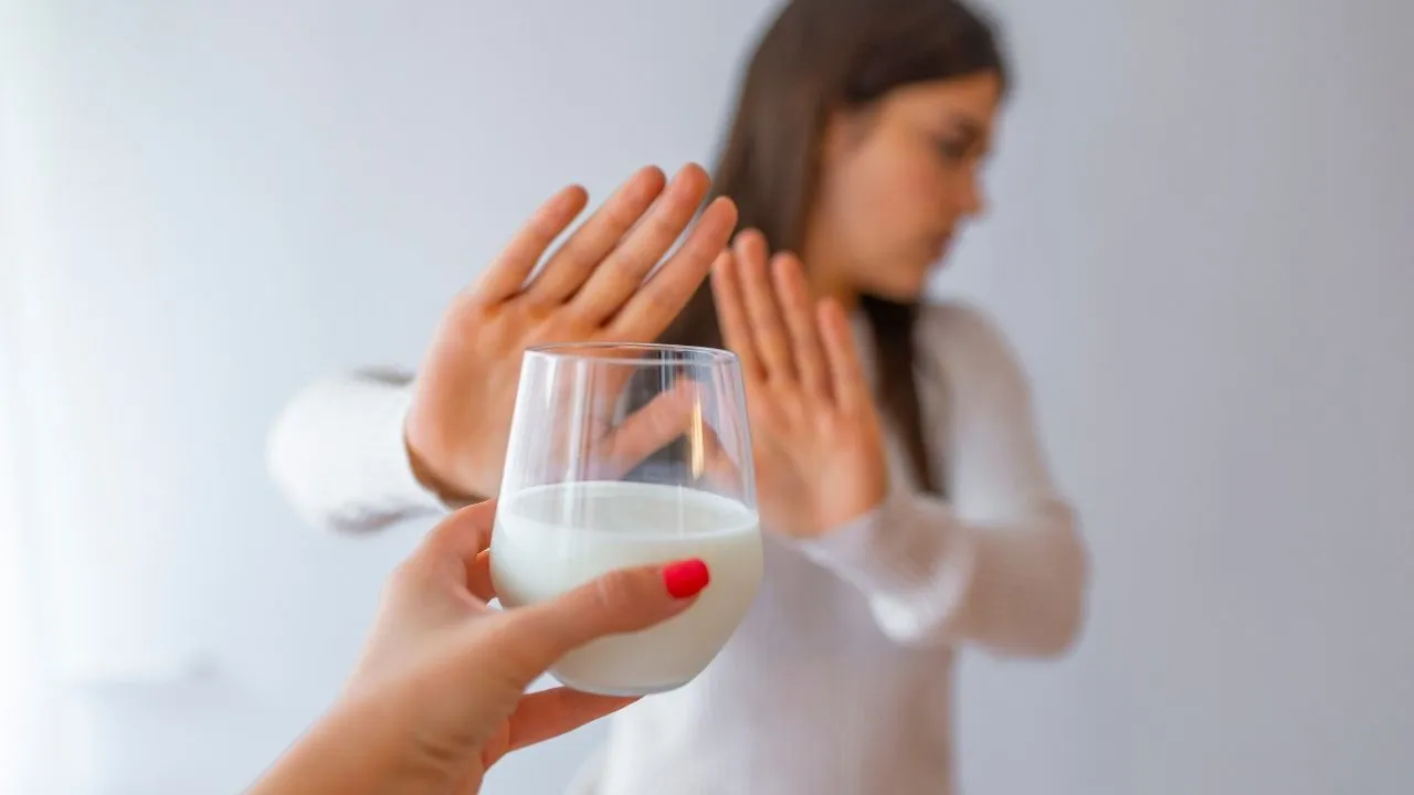 Donna che rifiuta un bicchiere di latte con un gesto della mano, a simboleggiare l'intolleranza al lattosio e la necessità di evitare i cibi che lo contengono.