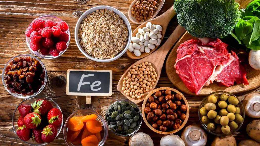 Una tavola imbandita con frutta, verdura, legumi, cereali e carne, alimenti ricchi di ferro.