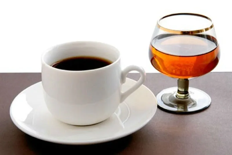 Una tazzina di espresso e un bicchiere di brandy, alcol e caffeina per una vita sociale durante il trattamento dimagrante con Mounjaro.