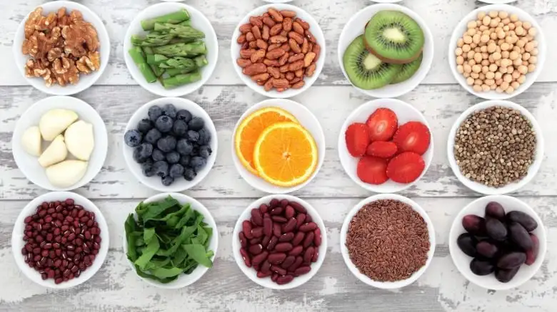 Ciotole bianche con altri alimenti ricchi di calcio oltre al latto e ai formaggi, come kiwi, broccoli, arancia, fragole.