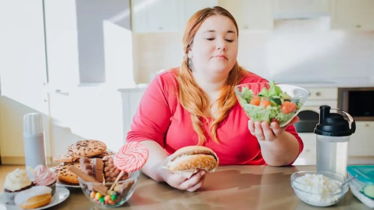 Una donna affetta da obesità che siede davanti ad un tavolo con a destra ciotole di alimenti sani e a sinistra non sani, facendo la cernita dei cibi da poter mangiare durante la terapia con mounjaro.