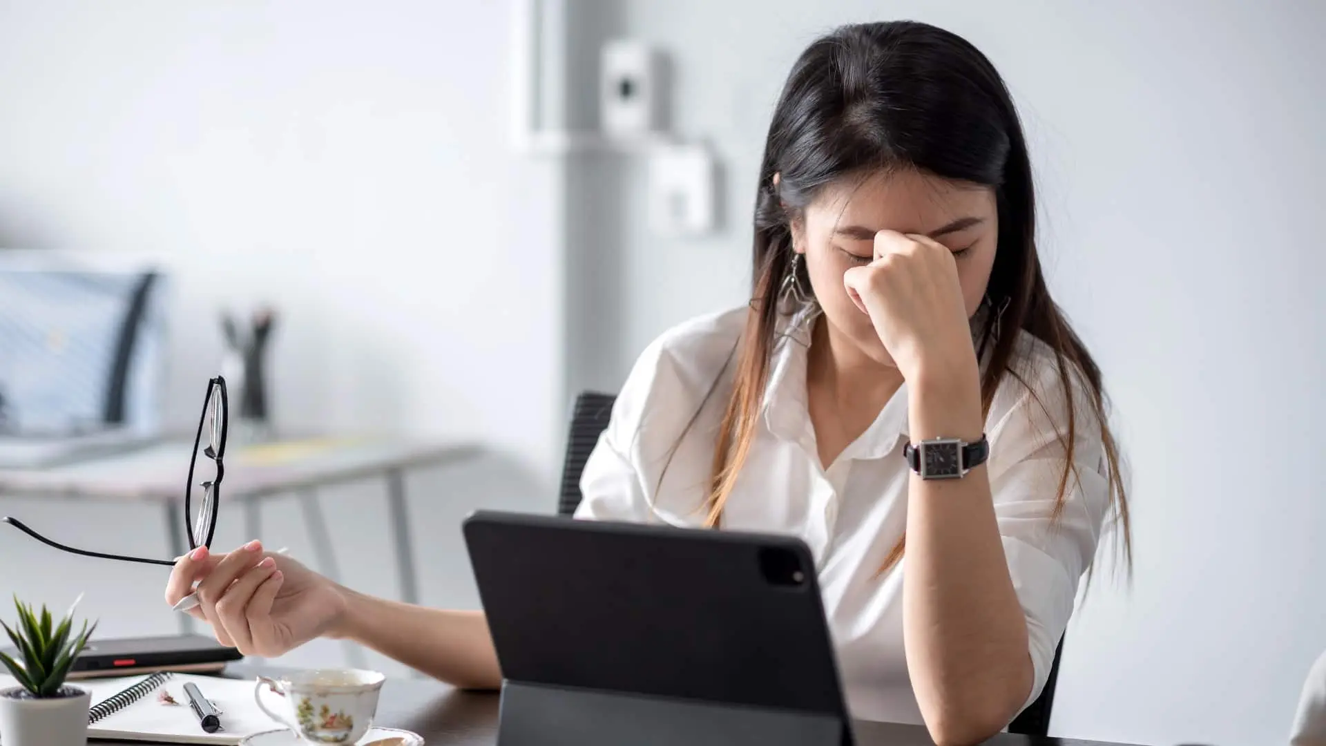 una donna seduta davanti al pc con la mano sul volto, stressata dal lavoro che deve imparare a gestire per la terapia con mounjaro.